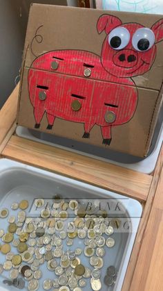 a cardboard box that has some coins in it and a pig on the front with eyes