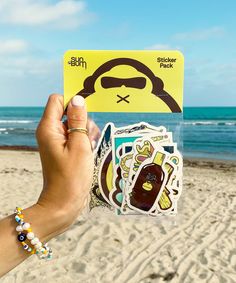 a person holding up a sticker on the beach