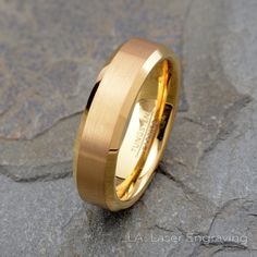 a gold wedding ring sitting on top of a stone slabd ground with the word love written in it