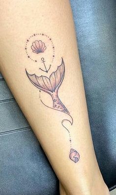 a woman's leg with a mermaid tattoo on the side of her body and an anchor