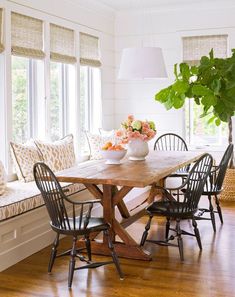 a dining room table with four chairs and a potted plant in the corner on one side