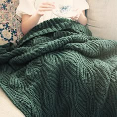 a woman sitting on a couch holding a cup