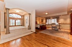 a large living room with wood floors and white walls, along with a jacuzzi tub