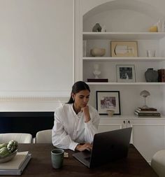 a woman sitting at a table using a laptop computer