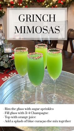 three glasses filled with green liquid sitting on top of a metal tray next to a christmas tree