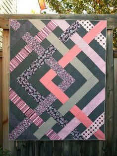 a quilt hanging from a wooden fence