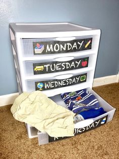 a white toy chest filled with clothes on top of a carpeted floor