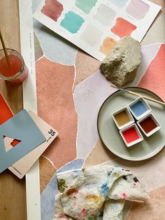 an assortment of paint samples and paints on a table with watercolor swatches, paper napkins, and other art supplies