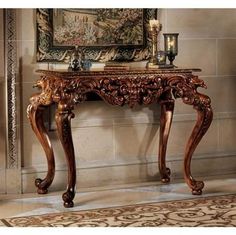 an ornately decorated console table in front of a wall with a painting on it