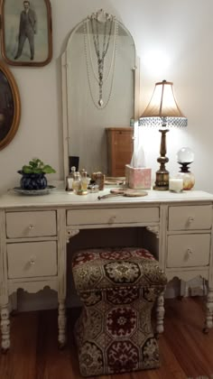 a white desk with a mirror, stool and jewelry on it in front of a lamp