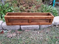 a wooden planter sitting on top of a grass covered field next to a stone wall