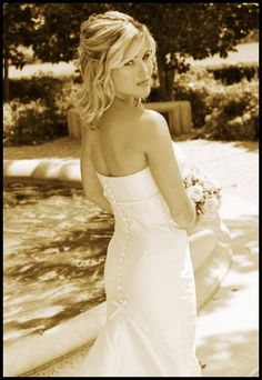 a woman in a white dress is standing outside