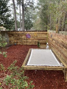 a wooden fenced in area with a white sheet on the ground next to it