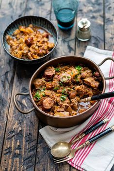 two bowls filled with food sitting on top of a wooden table next to silverware