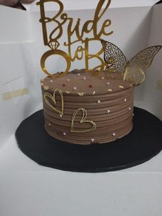 a chocolate cake with gold lettering and a butterfly on top