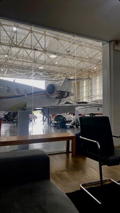 an airplane on display in a museum with people looking at it and two chairs sitting next to each other