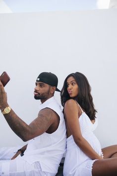 a man and woman sitting on the ground taking a selfie with a cell phone