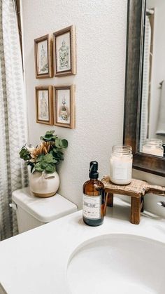 a bathroom with a sink, mirror and pictures on the wall above it's counter