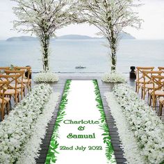 an aisle decorated with white flowers and greenery for a wedding ceremony by the water