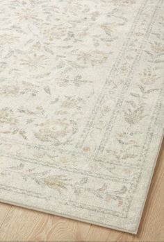 a white rug with an intricate design on the top and bottom, sitting on a wooden floor