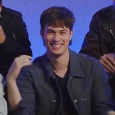 a smiling young man sitting next to two other men