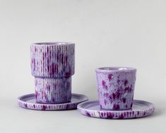 two purple cups and saucers sitting next to each other