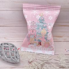 a pink bag with an image of a christmas tree on it next to a white lace doily