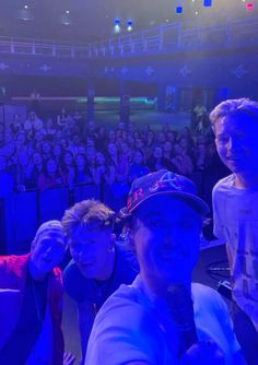 a group of young men sitting next to each other in front of a crowd at a concert