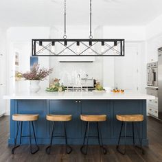 three stools sit in front of an island with blue cabinets and white countertops