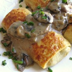 a white plate topped with crepes covered in mushrooms