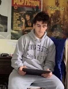 a young man sitting on top of a bed holding a tablet