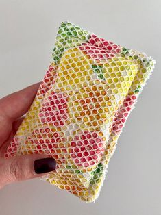 a woman's hand holding up a piece of fabric covered in multicolored circles