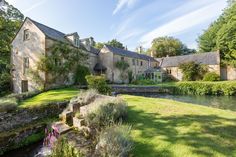 a large house sitting next to a river in the middle of a lush green field