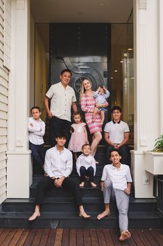 a group of people sitting on steps in front of a door with their arms around each other