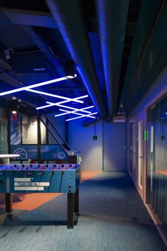 a pool table in the middle of a room with blue lights on it and windows