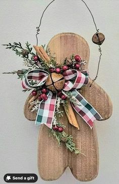 a wooden bear decoration hanging from the side of a wall with holly and berries on it