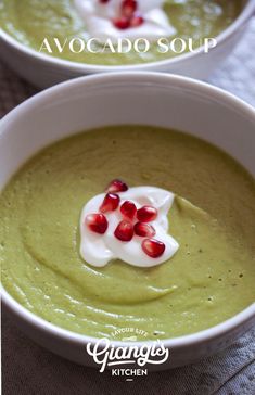 two white bowls filled with green soup and topped with pomegranate on top