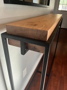 a wooden table sitting on top of a hard wood floor next to a white wall