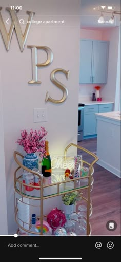 a gold bar cart with bottles and glasses on it in the corner of a room