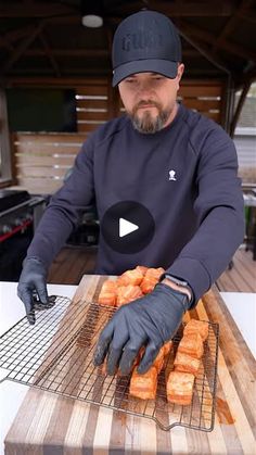 a man in black shirt and gloves cooking donuts on grill