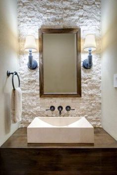 a bathroom sink sitting under a mirror next to a wall mounted faucet and two lights