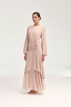 Introducing the Narjis Side Rouched Maxi Dress in Jasmine Pink. Embrace the exquisite side rouched detailing and asymmetrical tier design that flatters every figure. With elegant balloon sleeves and a flowy chiffon fabric, this dress is a timeless piece for any occasion. Elevate your wardrobe with this luxurious dress. Model is 5'7" and is wearing size XS/58". Feminine Lantern Sleeve Ruched Dresses, Billowy Ruched Midi Dress For Evening, Feminine Long Sleeve Ruched Maxi Dress, Billowy Ruched Midi Dress For Party, Feminine Ruched Dress With Balloon Sleeves, Modest Ruched Dress With Puff Sleeves, Elegant Dress With Ruffle Hem And Lantern Sleeves, Elegant Long Sleeve Dresses With Ruched Sides, Billowy Ruched Maxi Dress With Puff Sleeves