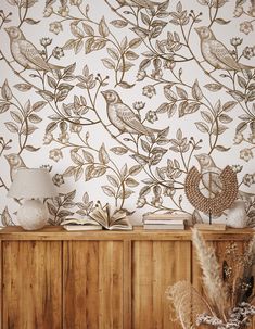 a wooden cabinet sitting next to a wall covered in birds and leaves on it's side