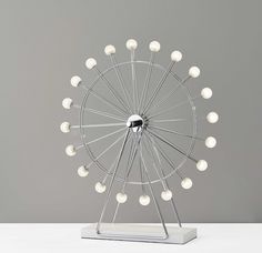 a light up ferris wheel with white balls in it's center on a table