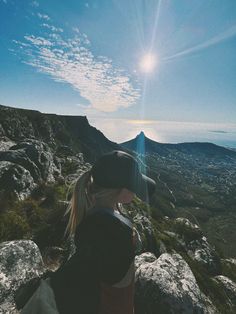 a woman sitting on top of a rock covered hillside