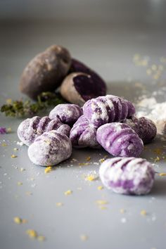 purple and white donuts sitting on top of a table next to some dried flowers