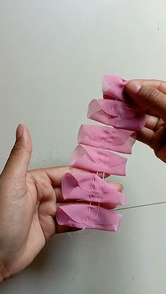 two hands are holding pink strips of paper