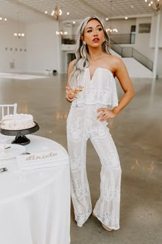 a woman standing in front of a table with a cake on it and a glass of wine