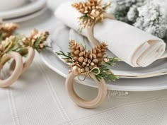 napkin rings with pine cones on them are sitting on a table set for christmas dinner