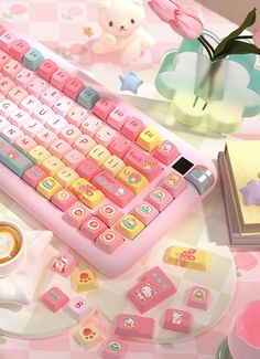 a pink and yellow keyboard sitting on top of a table next to a cup of coffee